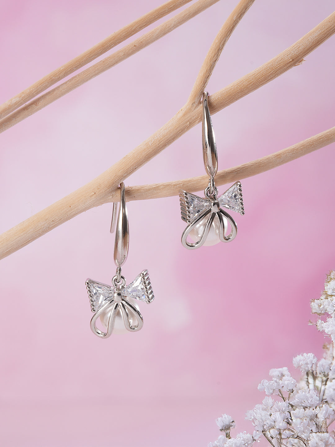 Jazz And Sizzle Rhodium Plated Bow Shaped Pearl Studded Drop Earrings