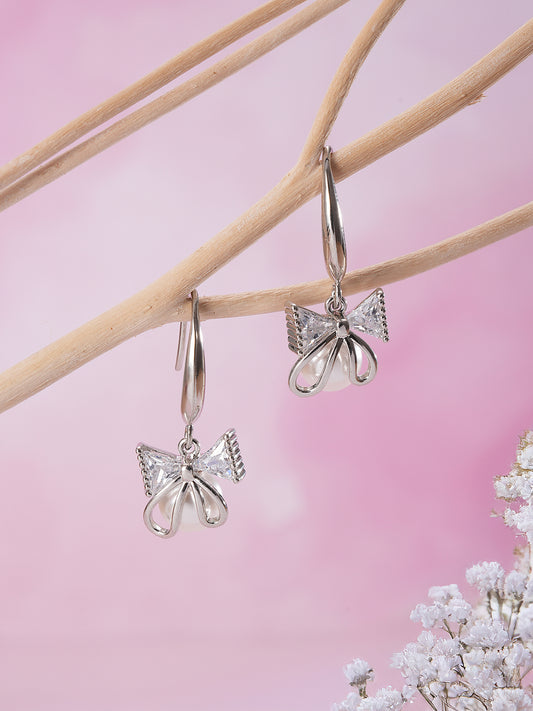 Jazz And Sizzle Rhodium Plated Bow Shaped Pearl Studded Drop Earrings